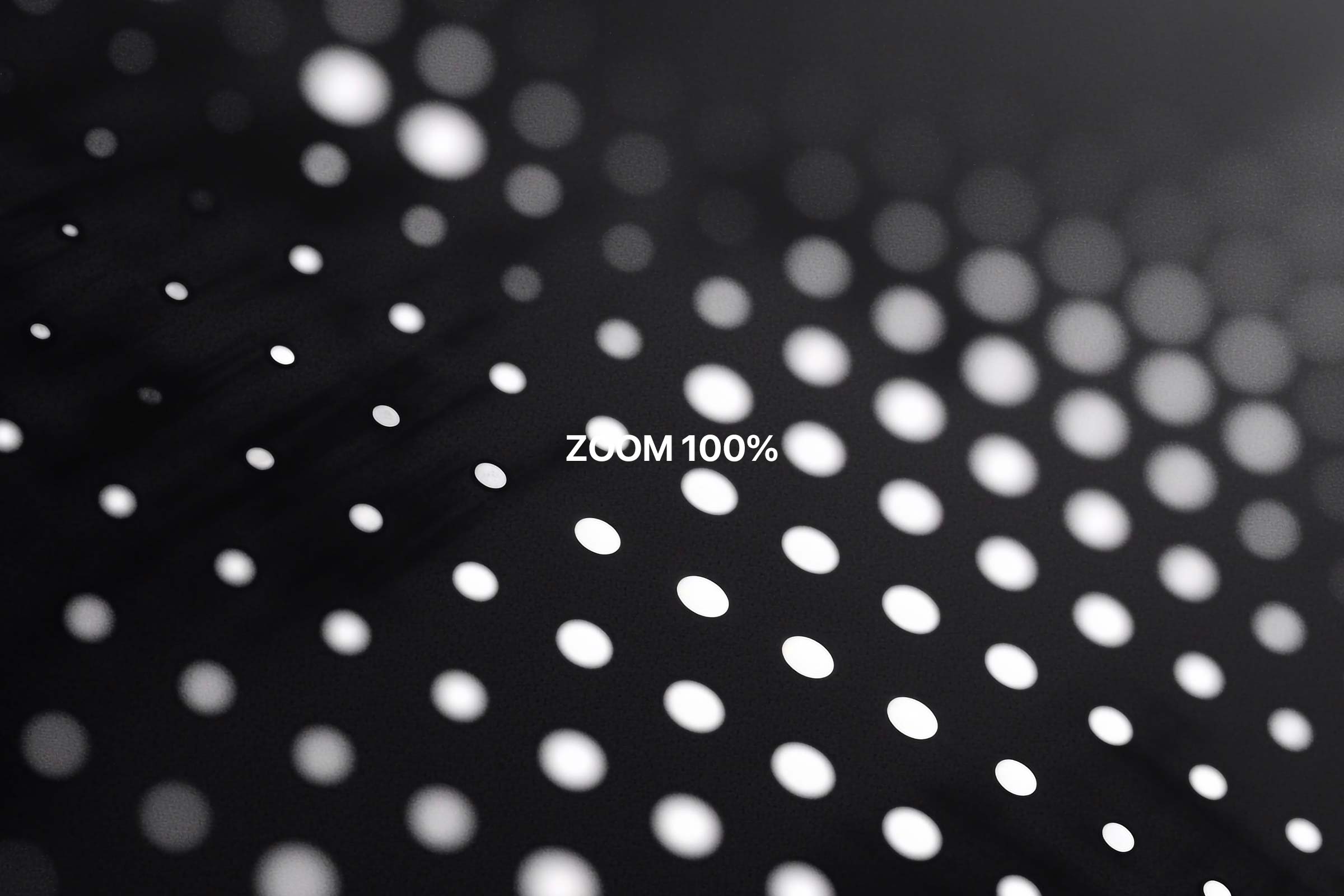 Close-up view of a dot-matrix display background with 'ZOOM 100%' text overlay, showing the fine detail and clarity of the white dots against the black backdrop